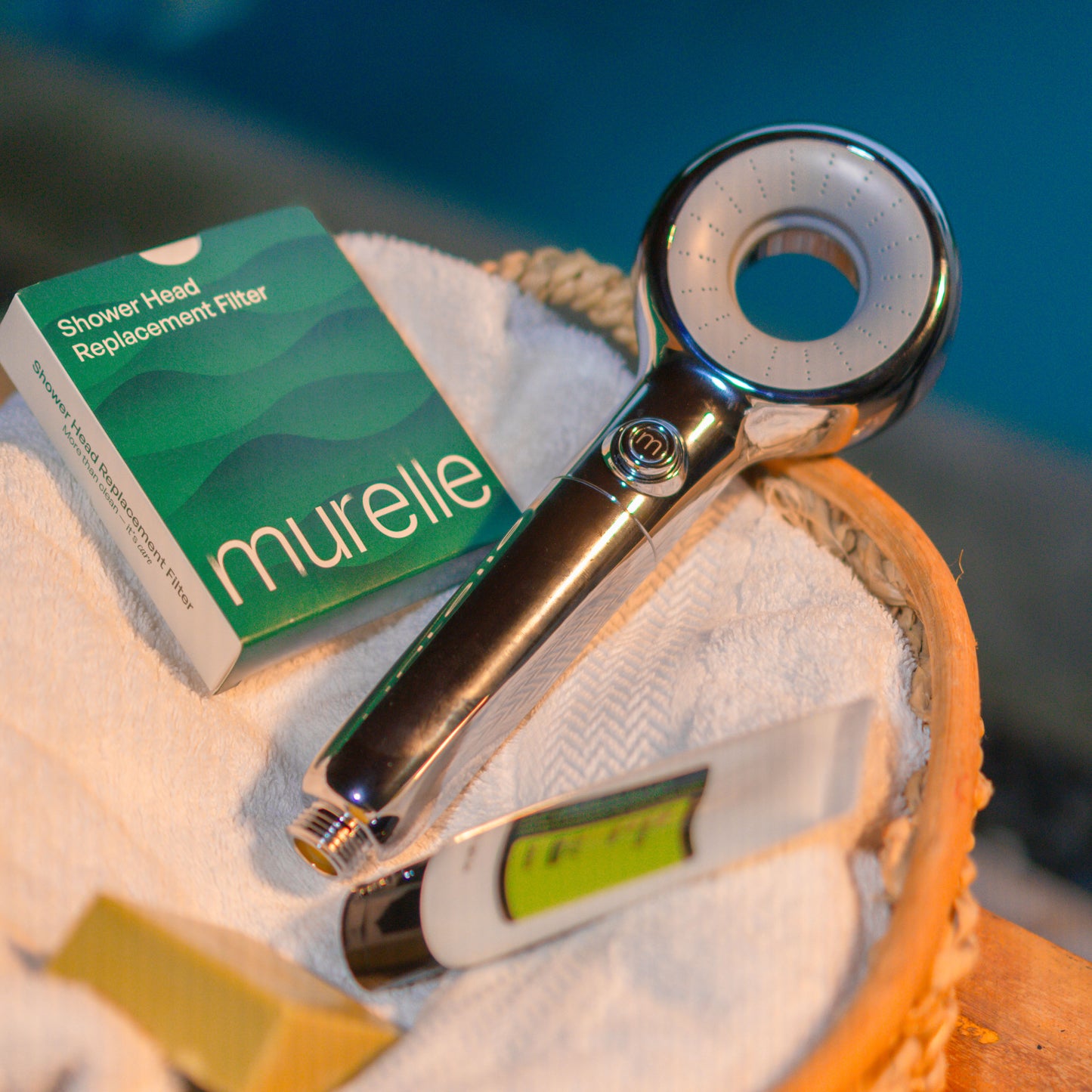 Chrome shower head and packaging labeled 'murelle' on a towel with a blurred background.